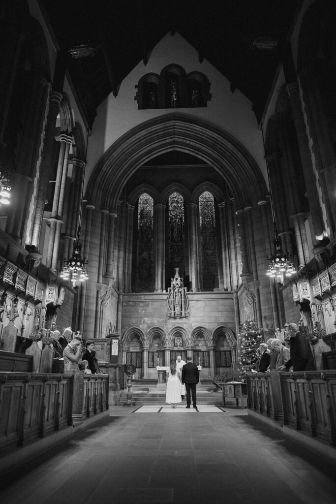 A black and white photograph showing a grand church at a wedding ceremony.